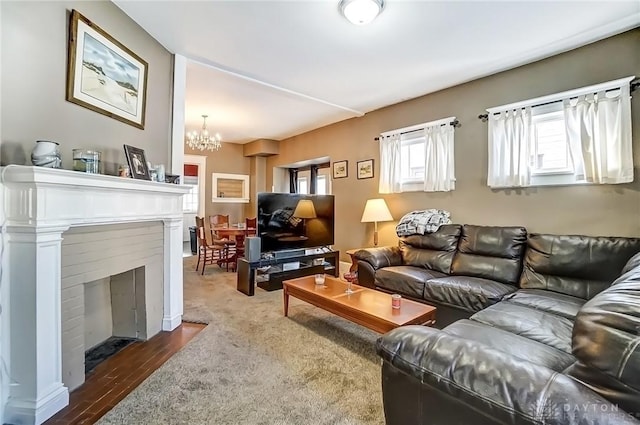 living room with a fireplace with flush hearth, dark wood-type flooring, and an inviting chandelier