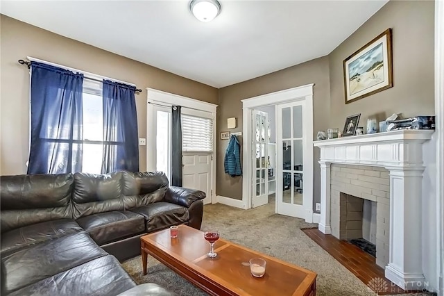 living room with a brick fireplace, french doors, and baseboards