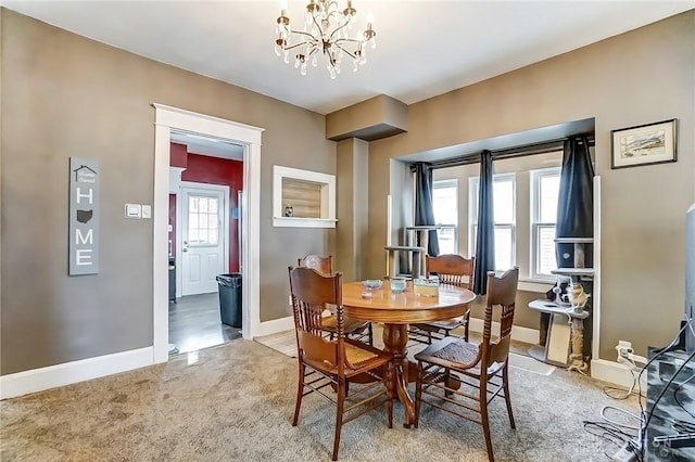 dining room featuring a notable chandelier, light colored carpet, and baseboards