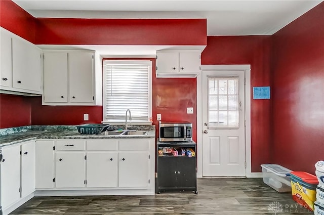 kitchen with stainless steel microwave, white cabinets, and dark wood-style flooring