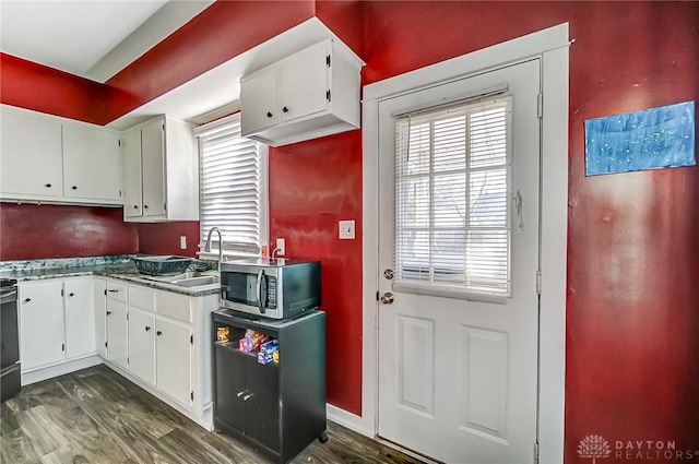 kitchen with dark wood finished floors, stainless steel microwave, white cabinetry, and a sink