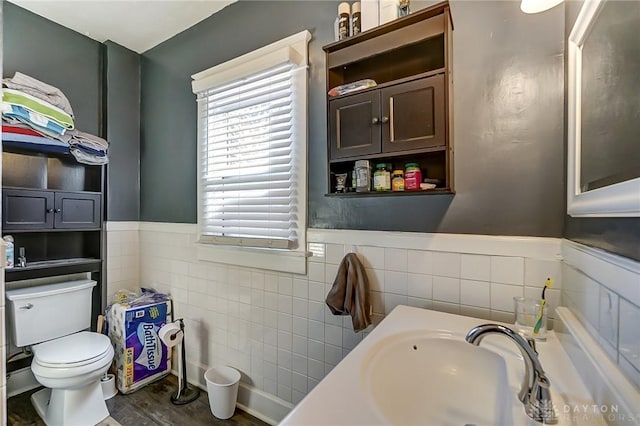 bathroom featuring wood finished floors, wainscoting, toilet, and a sink