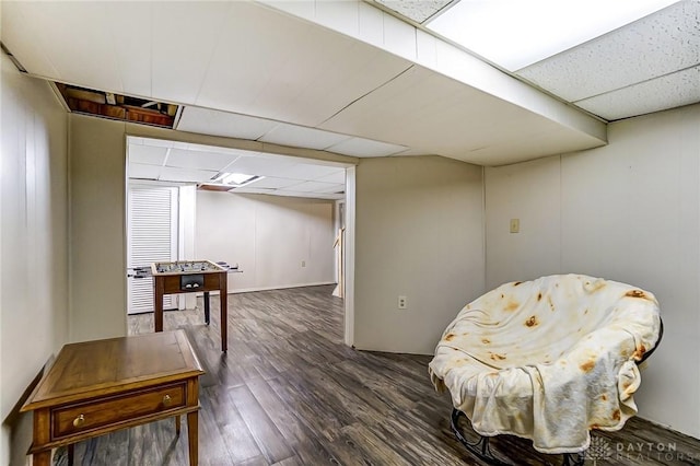 living area featuring dark wood-type flooring and a drop ceiling