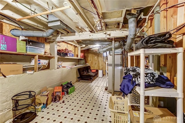 unfinished below grade area with tile patterned floors, heating unit, and wood walls