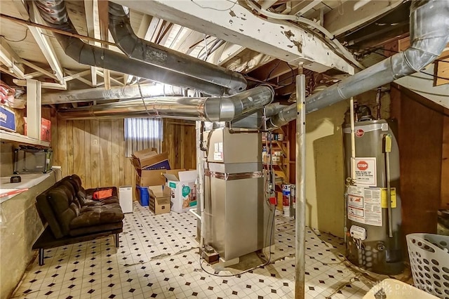 basement with tile patterned floors, heating unit, water heater, and wood walls