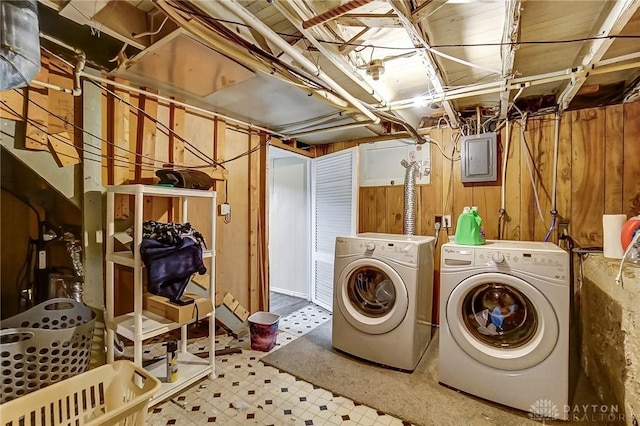 laundry room featuring tile patterned floors, electric panel, washing machine and dryer, wooden walls, and laundry area