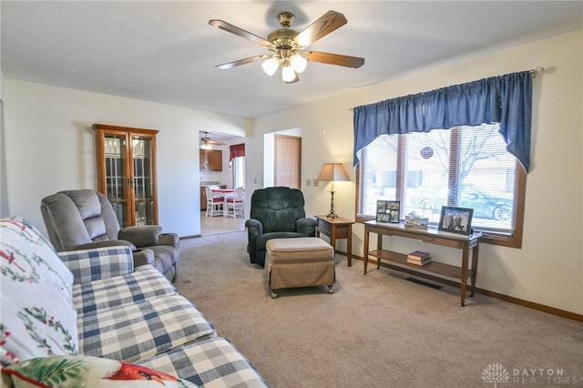 living area with carpet flooring, baseboards, and ceiling fan