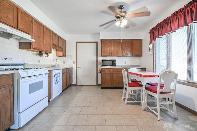 kitchen featuring under cabinet range hood, white appliances, light countertops, and a sink