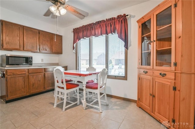 kitchen with stainless steel microwave, brown cabinets, baseboards, and a ceiling fan