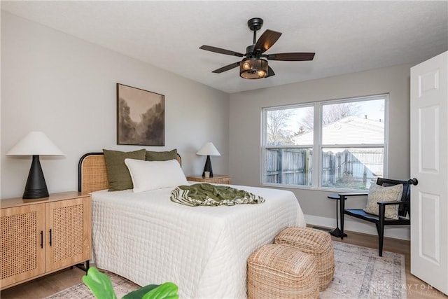 bedroom featuring a ceiling fan, baseboards, and light wood finished floors