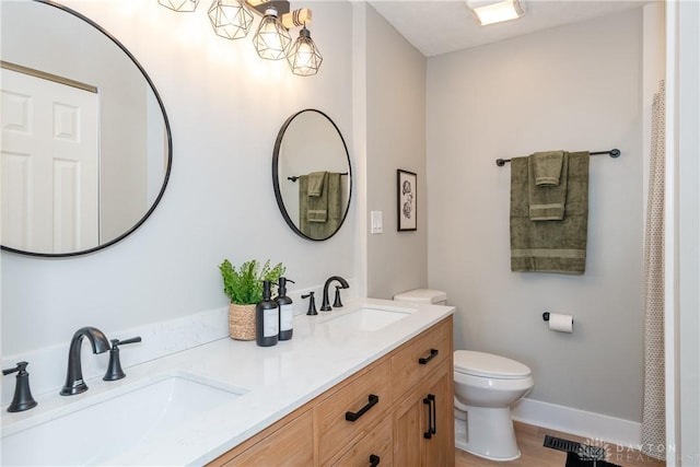 full bath featuring double vanity, toilet, baseboards, and a sink