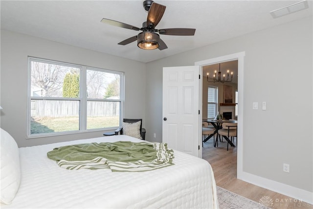 bedroom with visible vents, ceiling fan with notable chandelier, baseboards, and light wood-style floors