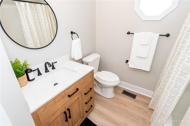 full bathroom with vanity, wood finished floors, visible vents, baseboards, and toilet