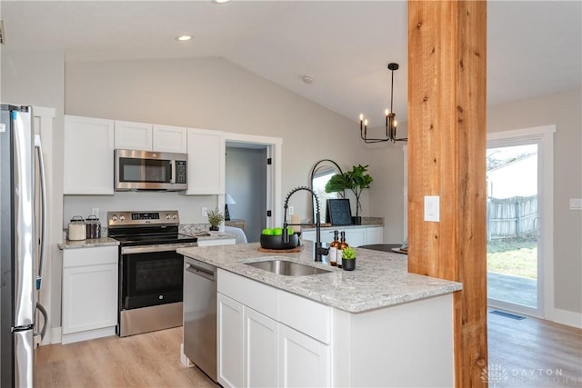 kitchen with a center island with sink, a sink, appliances with stainless steel finishes, white cabinets, and light wood finished floors