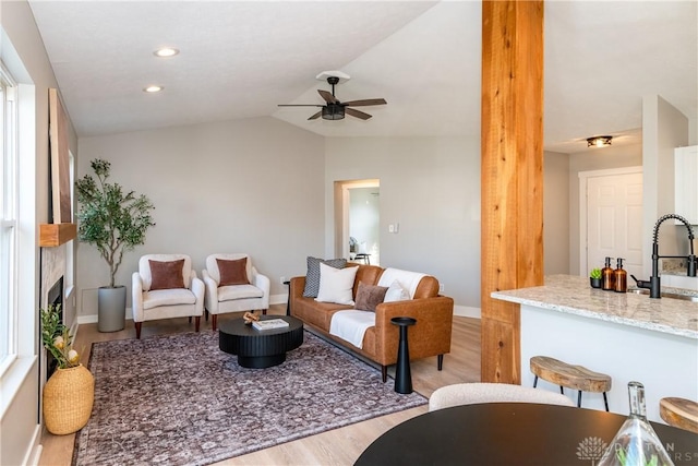 living room with lofted ceiling, baseboards, and light wood-type flooring