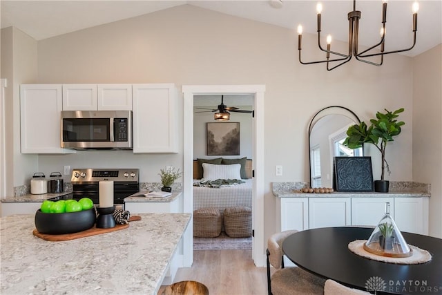 kitchen featuring decorative light fixtures, ceiling fan with notable chandelier, light wood-style flooring, stainless steel appliances, and white cabinetry