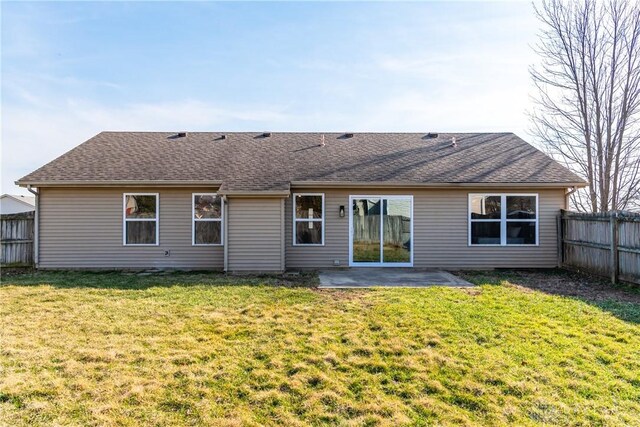 rear view of property featuring a patio, a yard, fence, and roof with shingles