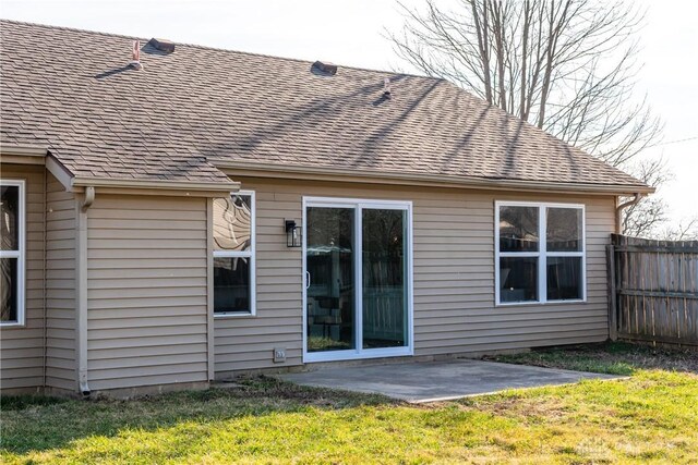 back of property with a patio area, a lawn, roof with shingles, and fence