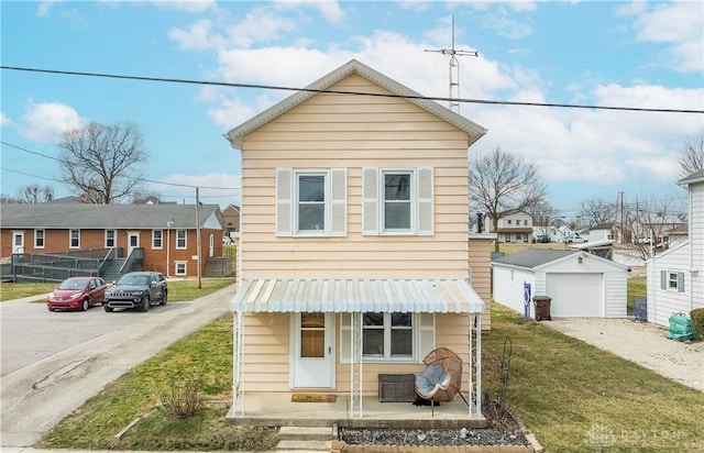 view of front of property with a garage, an outbuilding, covered porch, and a front lawn