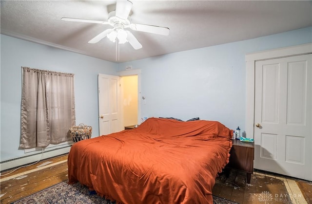 bedroom with a baseboard heating unit, hardwood / wood-style floors, and a ceiling fan