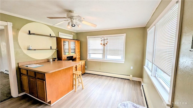 134 S Harrison St, New Madison, OH 45346 - kitchen with a baseboard heating unit, light wood-type flooring, a baseboard radiator, a kitchen bar, and a ceiling fan