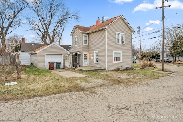 exterior space featuring a detached garage, a chimney, and driveway