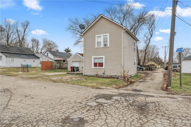 back of property with driveway, a garage, and fence