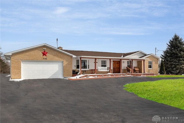 single story home featuring brick siding, driveway, an attached garage, and a front yard