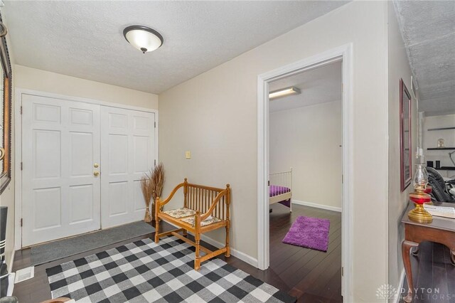 entryway with baseboards, a textured ceiling, and wood finished floors