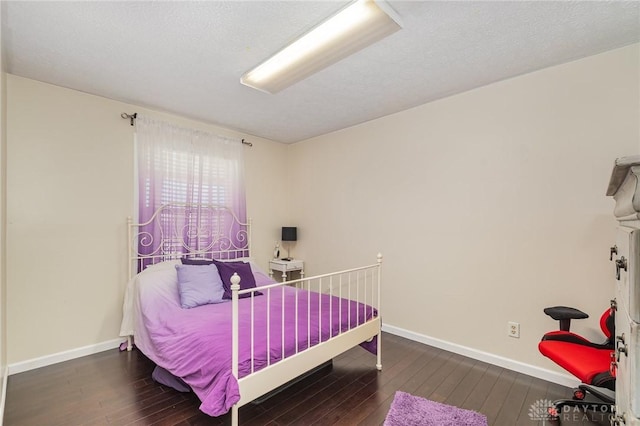 bedroom with hardwood / wood-style floors, baseboards, and a textured ceiling