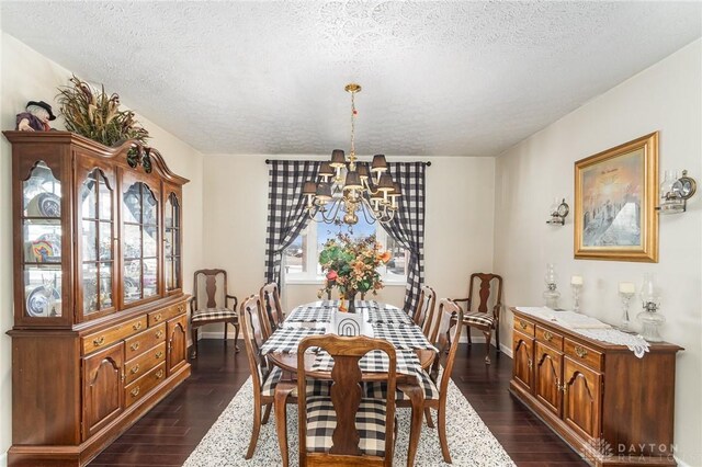 dining area featuring a notable chandelier, baseboards, dark wood-style flooring, and a textured ceiling