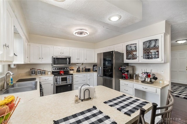 kitchen with stainless steel appliances, a sink, a textured ceiling, light countertops, and white cabinets