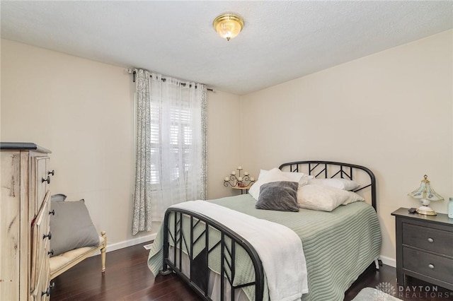 bedroom with baseboards, a textured ceiling, and wood finished floors