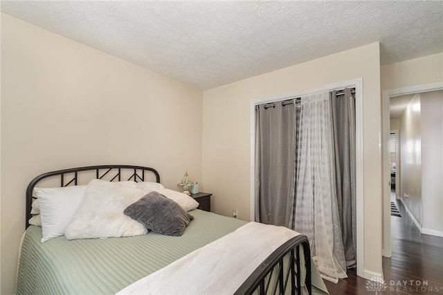 bedroom with baseboards, dark wood-style flooring, and a textured ceiling