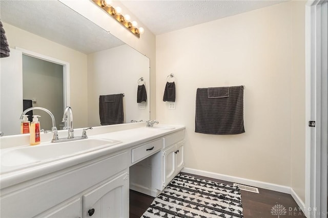 bathroom with double vanity, wood finished floors, baseboards, and a sink