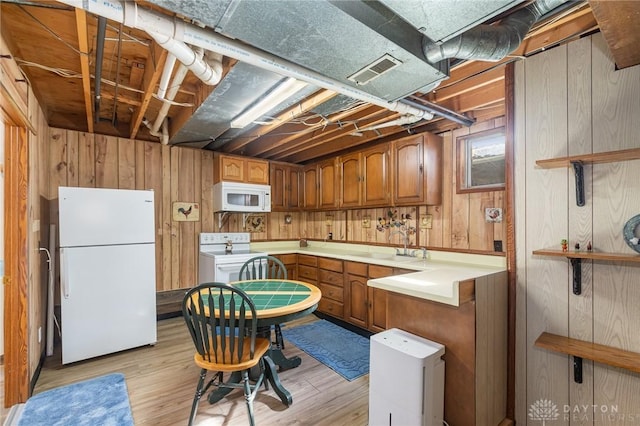 kitchen with white appliances, wooden walls, visible vents, light countertops, and brown cabinets