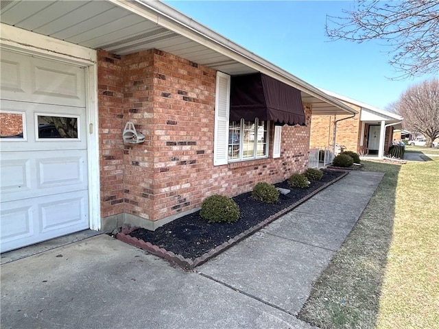 view of side of home featuring brick siding and an attached garage