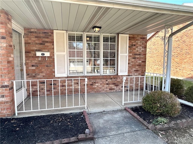 entrance to property featuring brick siding and covered porch