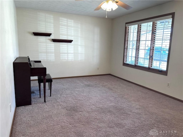 office space with carpet flooring, a textured ceiling, baseboards, and a ceiling fan