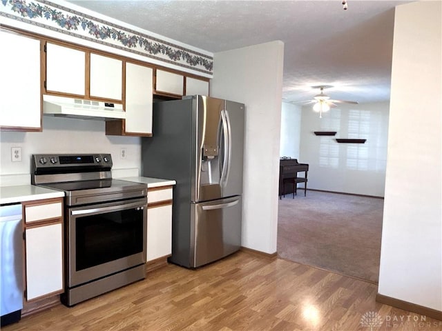 kitchen featuring light wood-type flooring, a ceiling fan, under cabinet range hood, stainless steel appliances, and light countertops