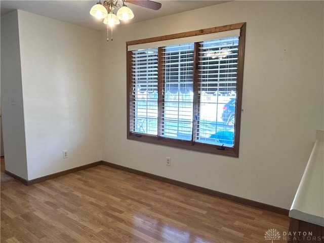 spare room featuring wood finished floors, baseboards, and ceiling fan