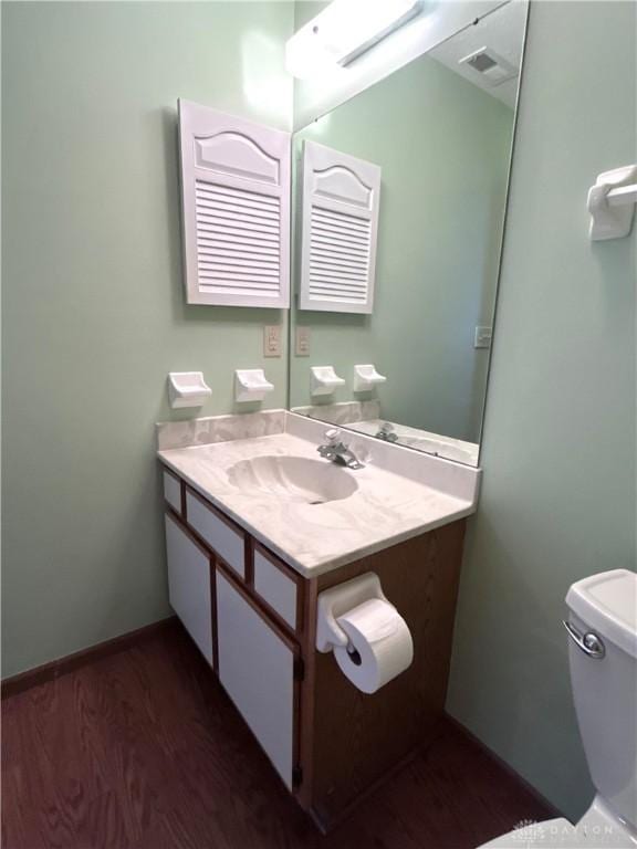 bathroom with vanity, wood finished floors, visible vents, baseboards, and toilet