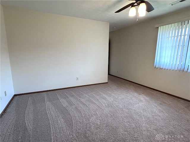 carpeted spare room featuring a ceiling fan, visible vents, and baseboards