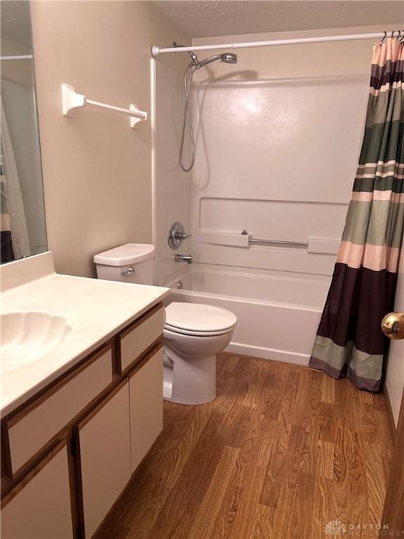 full bathroom with vanity, toilet, wood finished floors, and shower / bath combo with shower curtain