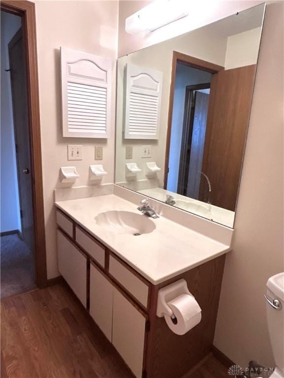 half bath featuring toilet, wood finished floors, and vanity