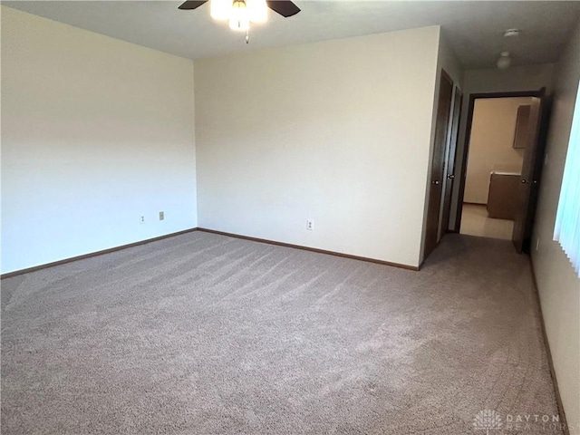 unfurnished room featuring light carpet, a ceiling fan, and baseboards