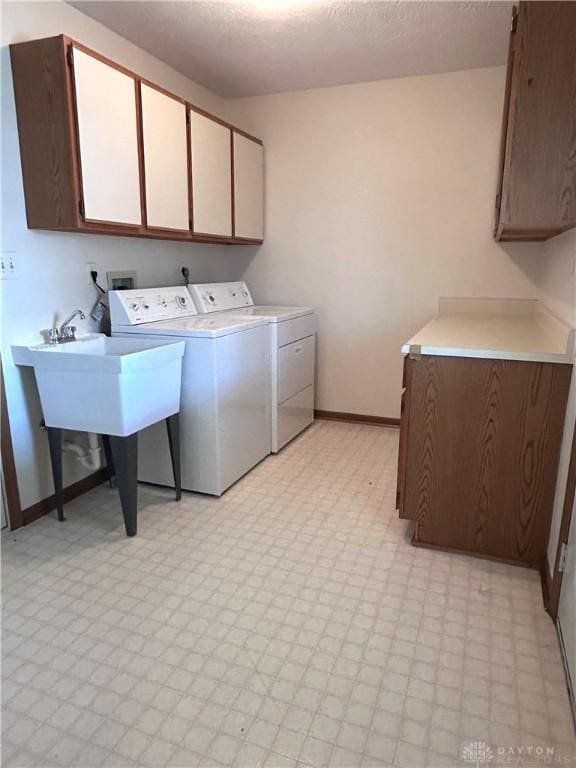 washroom with a textured ceiling, cabinet space, separate washer and dryer, baseboards, and light floors