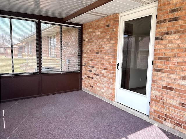 unfurnished sunroom featuring beamed ceiling