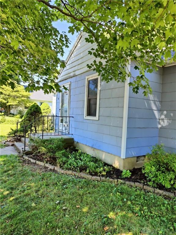 view of side of home with crawl space and a lawn