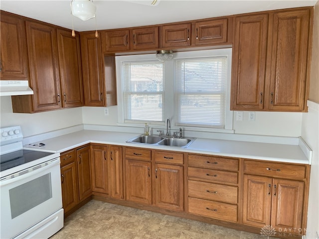 kitchen with extractor fan, light countertops, brown cabinetry, electric range, and a sink